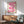 May include: Framed poster with pink gradient ribbon design forming flowing S-curves on cream background, displayed above mid-century modern wood credenza with ceramic table lamp. Green upholstered armchair with wooden frame sits nearby in bright, sunlit room with white walls and hardwood floors.