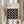 May include: Person in beige ruffled sleeve top holding framed Bauhaus poster against white curtained window. Poster features black background with 16 cream circles arranged in 4x4 grid, text about modernism and abstract arts 1919-1933. Light wooden frame, dried pampas grass visible on left side.