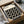 May include: Black and white geometric poster with repeating circles pattern in black frame, nestled in cardboard packaging with white tissue paper and wooden dowels for shipping protection, displayed on neutral surface
