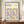 May include: Framed Bauhaus-inspired poster with colorful geometric circles in a grid pattern, featuring vibrant blues, yellows, pinks, and oranges on cream background. Dark wood frame sits on wooden sideboard beside white ceramic vase and stacked books in bright modern interior with white paneled walls.