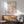 May include: Framed Bauhaus poster with colorful geometric circles in various split-color combinations hanging above a mid-century modern wooden credenza. Green upholstered armchair with wooden arms sits nearby, along with a small round coffee table and white ceramic table lamp. Bright natural light creates shadows on white wall, showcasing the poster's vibrant blues, yellows, oranges, purples, and pinks in a clean, minimalist room setting.