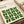 May include: Framed Bauhaus-inspired poster with green geometric leaf pattern arranged in a grid, featuring cream background and black typography. Modern minimalist design displayed on white surface with rolled papers nearby, showcasing clean lines and abstract botanical motifs in forest green color.