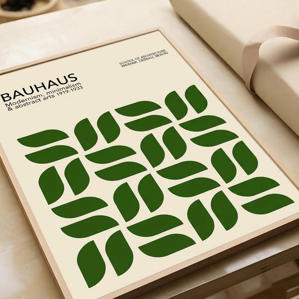 May include: Framed Bauhaus-inspired poster with green geometric leaf pattern arranged in a grid, featuring cream background and black typography. Modern minimalist design displayed on white surface with rolled papers nearby, showcasing clean lines and abstract botanical motifs in forest green color.