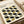 May include: Minimalist geometric poster with repeating pattern of black and olive green oval shapes arranged in rows on cream background, displayed in thin wooden frame on neutral surface beside rolled white paper tube