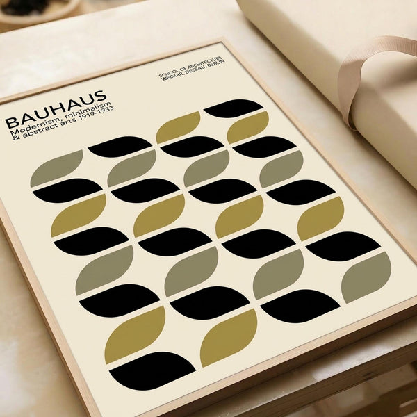 May include: Minimalist geometric poster with repeating pattern of black and olive green oval shapes arranged in rows on cream background, displayed in thin wooden frame on neutral surface beside rolled white paper tube