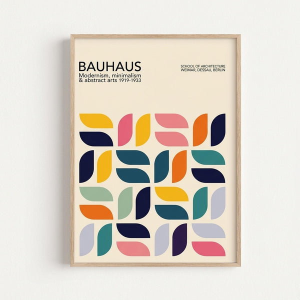 May include: Framed poster with cream background featuring geometric pattern of colorful half-circle and leaf-like shapes in yellow, pink, orange, navy, teal, sage green, and purple. Text reads "BAUHAUS" with "Modernism, minimalism & abstract arts 1919-1933" and "School of Architecture Weimar, Dessau, Berlin." Light wood frame against white wall.