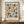 May include: Framed geometric poster with colorful semicircles and circles in muted pink, blue, green, orange and navy arranged in a grid pattern on cream background. Text reads "Bauhaus 1919-1933 School of Arts & Crafts" at bottom. Displayed on wooden sideboard next to small white ceramic vase and stacked books against white paneled wall.