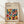 May include: Framed poster with geometric pattern of colorful semicircles and quarter circles in earthy tones including orange, teal, burgundy, olive, and coral on cream background. Text reads "BAUHAUS Modernism, minimalism & abstract arts 1919-1933" and "SCHOOL OF ARCHITECTURE WEIMAR, DESSAU, BERLIN." Natural wood frame leans against white wall on light wooden floor with soft window shadows.