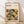 May include: Framed poster with geometric abstract design featuring overlapping circles in orange, yellow, teal, olive green, and black creating a repeating pattern. Text reads "BAUHAUS Modernism, minimalism & abstract arts 1919-1933" and "SCHOOL OF ARCHITECTURE WEIMAR, DESSAU, BERLIN". Light wood frame leaning against white wall on wooden floor with natural shadows.