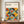 May include: Framed Bauhaus-style geometric poster with overlapping circles in orange, yellow, teal, olive green, and black creating repeating patterns. Modern art print displayed on wooden sideboard next to white ceramic vase and stacked books in minimalist room with white walls and crown molding.
