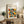 May include: Framed geometric poster with colorful overlapping circles in orange, yellow, teal, and gray displayed on rustic wooden sideboard alongside fern plant, books, and ceramic vase in bright modern living room setting