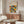 May include: Framed Bauhaus poster with colorful geometric circles in orange, yellow, teal, and black displayed above a mid-century modern wood credenza. Scene shows minimalist living room with white curved chair, glass-top coffee table, and contemporary lamp. The poster features overlapping circular patterns in a grid layout with vintage modernist typography.