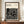 May include: Framed Bauhaus-inspired poster with black geometric maze-like pattern on cream background, displayed on wooden sideboard next to white ceramic vase and stacked books in elegant room with white paneled walls and crown molding.
