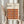 May include: Person holding framed Bauhaus poster featuring geometric pattern of overlapping circles in warm autumn colors - orange, burgundy, brown, and rust red tones. Light wood frame against cream background with dried pampas grass visible to the left. Clean minimalist styling with person wearing beige knit sleeves.