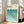 May include: Framed Bauhaus poster with geometric turquoise and teal semicircle pattern leaning against white wall next to beige armchair. Natural sunlight streams through windows onto light wooden floors. The minimalist design features overlapping arched shapes in gradient blues on cream background within thin wooden frame.