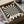 May include: Black and cream poster with radiating sunburst pattern creating optical illusion effect, displayed in brown cardboard box with protective tissue paper wrapping. Wooden dowels for hanging visible alongside, with dark glass jar in background on white surface.