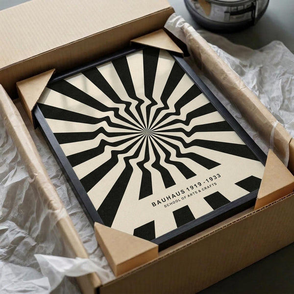 May include: Black and cream poster with radiating sunburst pattern creating optical illusion effect, displayed in brown cardboard box with protective tissue paper wrapping. Wooden dowels for hanging visible alongside, with dark glass jar in background on white surface.