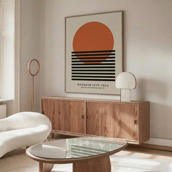 May include: Modern living room with walnut credenza displaying framed poster featuring orange sun above black horizontal stripes on cream background. White sculptural chair, glass coffee table, and copper floor lamp complete the mid-century inspired space with neutral walls.
