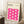 May include: Framed poster with cream background featuring bright pink wavy geometric pattern creating interlocking curved shapes. Text at top reads "BAUHAUS Modernism & abstract arts 1919-1933" and "SCHOOL OF ARCHITECTURE WEIMAR, DESSAU, BERLIN". Light wood frame leans against white wall next to wooden side table with white coffee cup, beige knit throw blanket visible on white textured rug.