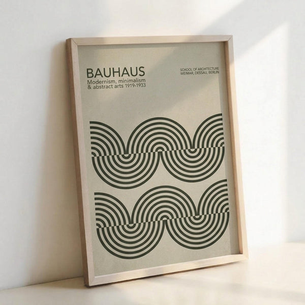 May include: Framed poster with cream background featuring geometric black concentric circles in wave-like pattern. Text reads "BAUHAUS Modernism, minimalism & abstract arts 1919-1933" and "SCHOOL OF ARCHITECTURE WEIMAR, DESSAU, BERLIN". Light wood frame leaning against white wall on white surface, showing minimalist Bauhaus design aesthetic.