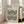 May include: Large framed poster with cream background featuring geometric black concentric semicircles in repeating wave pattern, text reading "BAUHAUS" and "Modernism, minimalism & abstract arts 1919-1933" at top, displayed in bright living room corner next to beige upholstered chair with throw pillows, white walls, and windows with natural light streaming in.