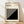 May include: Framed Bauhaus-inspired poster with black and white geometric design featuring diagonal stripes and bold triangle shape, displayed against white wall on wooden floor with natural lighting creating soft shadows across the scene.