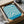 May include: Framed blue and cream abstract poster with flowing, wavy contour lines in Bauhaus style, packaged in brown cardboard box with protective tissue paper wrapping, photographed on white fabric surface next to glass object.