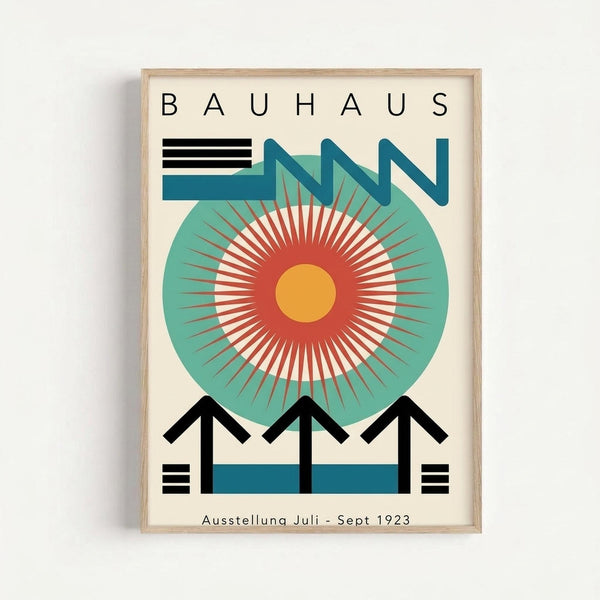 A framed Bauhaus-style poster featuring geometric design with a large circular motif in teal, red, and yellow radiating from center. Bold black angular shapes form arrow-like elements pointing upward, with horizontal stripes and the text "BAUHAUS" at top and "Ausstellung Juli - Sept 1923" at bottom. The modernist artwork uses a limited color palette of black, teal, coral red, and cream against a light wooden frame.