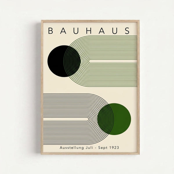 Framed modern art print with cream background featuring "BAUHAUS" text at top and "Ausstellung Juli - Sept 1923" at bottom. Design shows two geometric compositions: upper section has black circle with flowing green lines, lower section has green circle with curved black lines. Light wood frame against white wall.