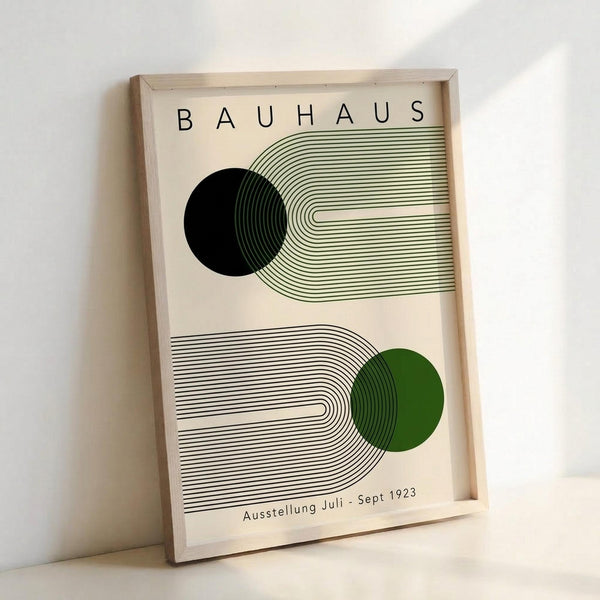 May include: Framed Bauhaus poster with geometric design featuring two curved line patterns - one in green lines with black circle, one in black lines with green circle. Clean minimalist artwork in light wood frame leaning against white wall on light surface.