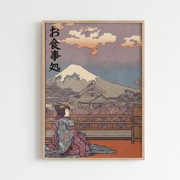 A framed Japanese ukiyo-e style artwork depicting a geisha in elaborate purple and teal patterned kimono sitting on a wooden veranda. Mount Fuji with snow-capped peak dominates the background landscape, with traditional Japanese buildings and blooming cherry trees scattered below. Orange and purple clouds drift across the sky. Black Japanese characters appear in the upper left corner. The print has the characteristic woodblock aesthetic with detailed linework and muted earth tones, displayed in
