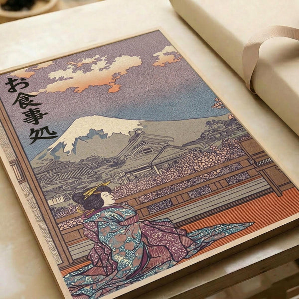 May include: Traditional Japanese woodblock print artwork displayed in an open book or portfolio on a white surface. The illustration shows a geisha in colorful patterned kimono sitting on a wooden veranda, with Mount Fuji visible in the background under a dramatic sky with pink and purple clouds. Japanese characters appear in the upper left corner. The print has the classic ukiyo-e style with fine line work and muted earth tones.