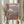 May include: Hands holding a framed Japanese ukiyo-e style print featuring a geisha in colorful kimono sitting on wooden platform with Mount Fuji and traditional buildings in background under cloudy sky. Person wearing cream ruffled sleeves holds dried wheat stalks beside the artwork against white curtained window.