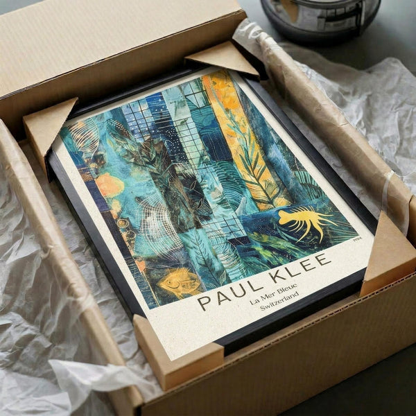 May include: Framed art print of Paul Klee's abstract composition featuring turquoise and blue tones with tropical palm fronds, geometric patterns, and golden accents, displayed in black frame inside cardboard shipping box with protective wrapping and packing materials on white surface.