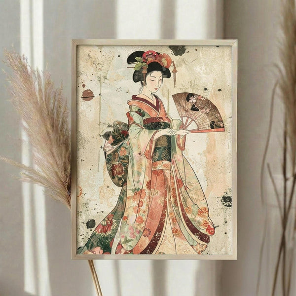 May include: Framed vintage-style Japanese geisha artwork displayed on easel beside dried pampas grass stems. The print features a woman in elaborate floral kimono holding decorative fan, rendered in soft coral, green and cream tones with distressed aging effects. Light wooden frame against neutral curtained background creates elegant home decor styling.