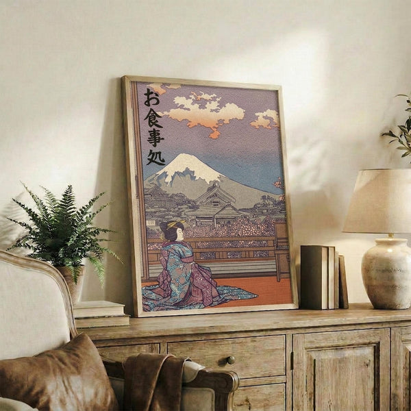 May include: Framed Japanese ukiyo-e style artwork featuring a geisha in colorful kimono seated on wooden platform with Mount Fuji and cloudy sky in background, displayed on rustic wooden console table alongside potted fern, ceramic vase, and books in warm-toned living room setting