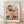 May include: Framed poster print leaning against white wall on light wood floor. Features colorful botanical illustration with stylized flowers, leaves and stems in red, yellow, teal, pink and purple on cream background. Text reads "YAYOI KUSAMA" at top and "Modern Art 1966" at bottom. Natural wood frame casting soft shadows on textured white wall.