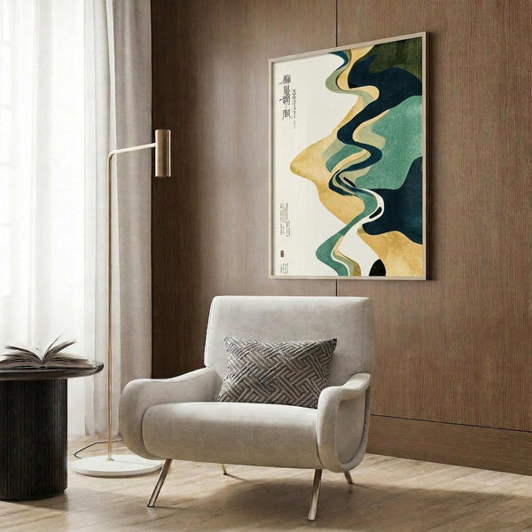 May include: Modern living room with beige upholstered armchair and geometric throw pillow. Large framed art print on wood-paneled wall features flowing abstract shapes in green, gold, and navy with Japanese calligraphy text. Golden floor lamp and dark round side table with open book complete the sophisticated interior setting.