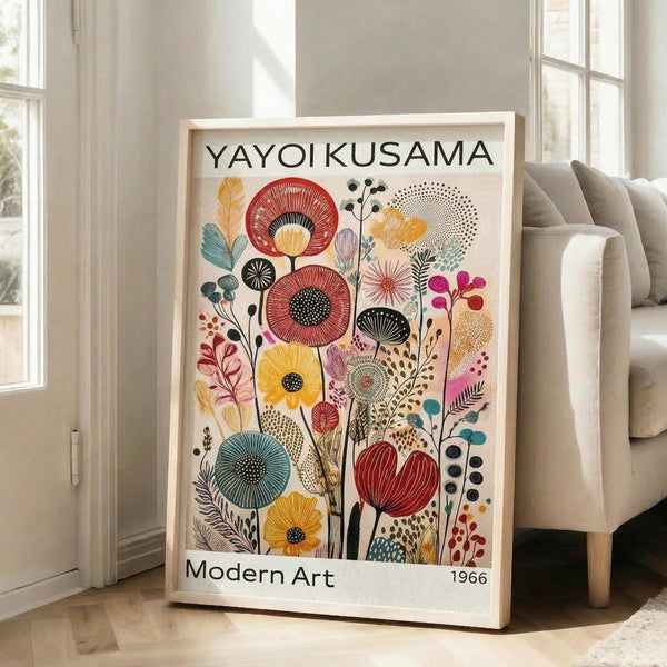 May include: Framed poster featuring colorful botanical illustration with stylized flowers and plants in red, yellow, teal, and pink tones against cream background, displayed on light wooden floor next to beige upholstered chair in bright room with white walls and large windows