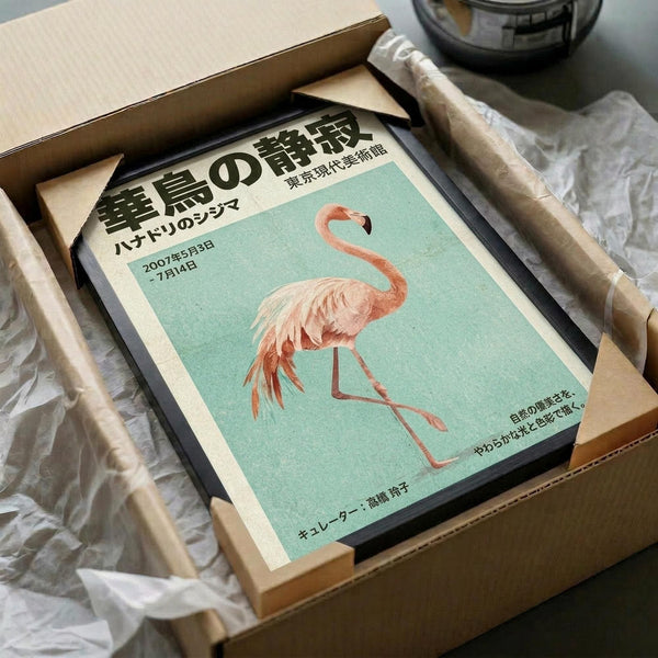 May include: Framed vintage-style Japanese poster featuring a pink flamingo on mint green background, displayed in black frame inside open cardboard shipping box with white tissue paper. Poster shows Japanese text and appears to be an art museum or exhibition advertisement from 2007. Box sits on white surface with decorative glass bowl visible in background.