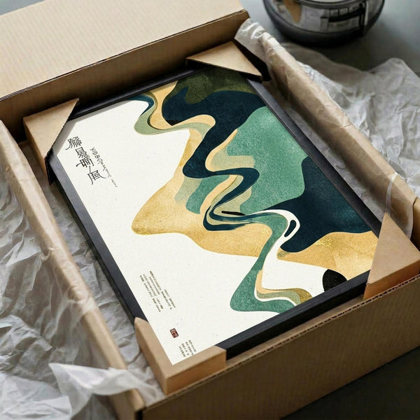 May include: Abstract flowing artwork in dark teal, sage green, golden yellow and white colors displayed in black frame, carefully packaged in brown cardboard box with protective tissue paper. Japanese calligraphy characters visible on left side of print. Wooden rolling pins and ceramic bowl partially visible in background, creating artistic flat lay composition on white fabric surface.