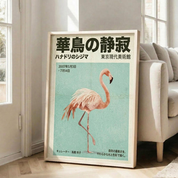 May include: Framed Japanese exhibition poster featuring pink flamingo on mint green background, displayed on light wooden floor against white wall beside beige upholstered chair. Poster shows Japanese text at top, dates 2007年5月3日-7月14日, and curator information at bottom. Natural lighting creates soft shadows in bright, minimalist room setting.
