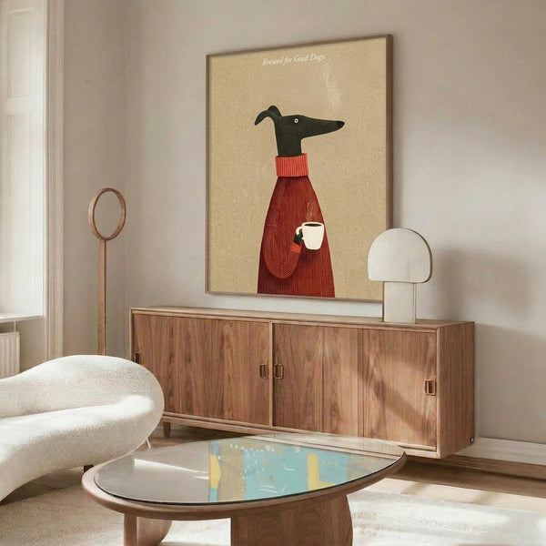 May include: Stylized illustration of a black greyhound wearing a red knit sweater and holding a white coffee cup, displayed in a thin frame above a walnut credenza in a modern living room with cream walls, white upholstered chair, and glass-top coffee table