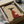 May include: Framed poster print in black frame showing minimalist illustration of black greyhound wearing red ribbed sweater with small white coffee cup design on chest, tan background with "Brewed for Good Dogs" text at top, displayed in cardboard shipping box with protective wrapping materials on white surface