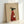 May include: Framed poster print leaning against white wall showing minimalist illustration of black greyhound wearing red ribbed turtleneck sweater and holding white coffee mug, with text "Brewed for Good Dogs" on beige textured background in natural wood frame