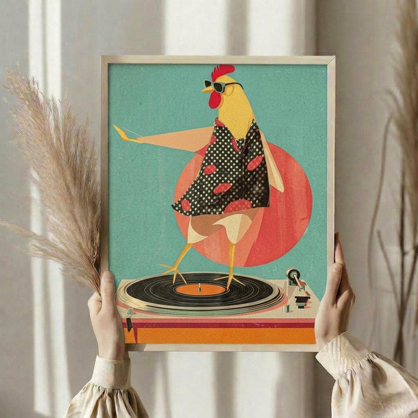 May include: Person in cream ruffled sleeves holding framed artwork showing a stylized rooster wearing sunglasses and polka dot outfit, dancing on a vintage turntable against turquoise background with coral circle. Dried pampas grass visible to left, neutral interior setting with white curtains.