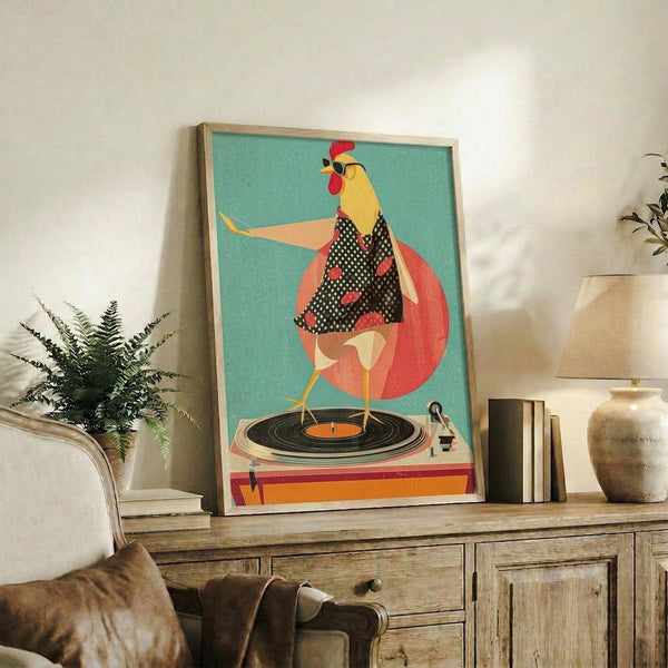 May include: Framed poster with turquoise background showing a stylized rooster in polka dot vest standing on a vinyl record turntable. The chicken has yellow body, red comb, and is positioned against a coral circle. Artwork displayed on rustic wooden sideboard with books, ceramic vase, and fern plant beside beige armchair in modern living room setting.