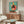 May include: Colorful poster showing a stylized chicken wearing sunglasses and polka dot clothing, dancing on a vinyl record turntable against a teal background with coral circle. Displayed above a mid-century walnut credenza in modern living room with white curved chair, brass floor lamp, oval glass coffee table, and white table lamp.