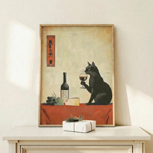 May include: Framed poster print displayed on light wood console table against white wall. Artwork shows black cat in Japanese ukiyo-e style holding wine glass, sitting at red-orange table with wine bottle, grapes, and cheese. Features aged beige background with Japanese text in red cartouche. Natural wood frame matches console. Small white gift box with greenery sits beside frame.