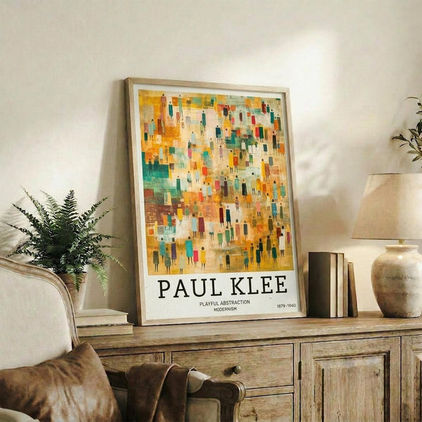 May include: Colorful abstract art poster with geometric figures in yellows, oranges, teals and earth tones, displayed in thin wooden frame on rustic wood sideboard. Room styled with fern plant, beige chair, ceramic vases and books creating warm, modern living space with white walls.
